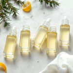 Small glass vials of pale golden aromatic oil arranged on a light stone surface
